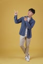 Portrait of happy handsome young asian man dressed casually pointing fingers at copyspace isolated on yellow background Royalty Free Stock Photo