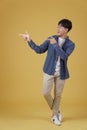 Portrait of happy handsome young asian man dressed casually pointing fingers at copyspace isolated on yellow background Royalty Free Stock Photo