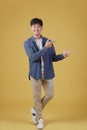 Portrait of happy handsome young asian man dressed casually pointing fingers at copyspace isolated on yellow background Royalty Free Stock Photo