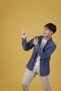 Portrait of happy handsome young asian man dressed casually pointing fingers at copyspace isolated on yellow background Royalty Free Stock Photo