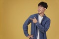 Portrait of happy handsome young asian man dressed casually pointing fingers at copyspace isolated on yellow background Royalty Free Stock Photo