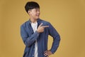 Portrait of happy handsome young asian man dressed casually pointing fingers at copyspace isolated on yellow background Royalty Free Stock Photo