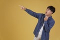 Portrait of happy handsome young asian man dressed casually pointing fingers at copyspace. yellow background Royalty Free Stock Photo
