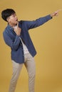 Portrait of happy handsome young asian man dressed casually pointing fingers at copyspace. yellow background Royalty Free Stock Photo