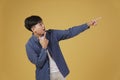 Portrait of happy handsome young asian man dressed casually pointing fingers at copyspace. yellow background Royalty Free Stock Photo