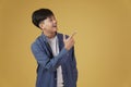 Portrait of happy handsome young asian man dressed casually pointing fingers at copyspace. yellow background Royalty Free Stock Photo