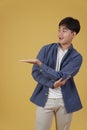 Portrait of happy handsome young asian man dressed casually presenting with open palm hand gesture at copyspace isolated on yellow Royalty Free Stock Photo
