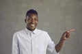 Portrait of happy handsome young black man smiling and pointing away with his finger Royalty Free Stock Photo