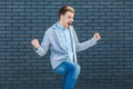 Portrait of happy handsome young blonde man in casual style standing, amazed, celebrating and rejoicing his victory and success Royalty Free Stock Photo