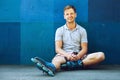 Happy handsome young roller in inline skates sitting Royalty Free Stock Photo