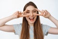 Portrait of happy and healthy girl shows peace, v-sign gesture near eyes and smiling joyful at camera, white background Royalty Free Stock Photo