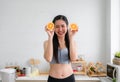 Portrait of happy healthy young woman in sportswear standing smile and holding orange sliced half in kitchen at home