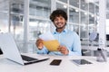 Portrait of a happy Hindu programmer inside the office, a businessman holds an envelope with a good news message in his