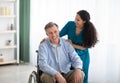 Portrait of happy impaired elderly man and his female nurse at retirement home. Professional medical care for seniors Royalty Free Stock Photo