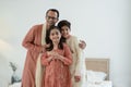 Portrait of happy Indian family standing in bedroom at home. Smart young father with little cute kids wearing traditional dress,