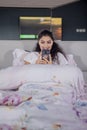 Happy Indian woman using mobile phone on bed Royalty Free Stock Photo