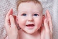 Portrait of a happy infant baby and mom hand. Mother stroking the face of a smiling toddler child on a sofa, six to seven months Royalty Free Stock Photo