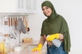 Cheerful muslim young woman cleaning dining table at kitchen Royalty Free Stock Photo