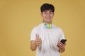 Portrait of happy joyful cheerful young asian man wearing headphones listening to music on smartphone and dancing isolated on Royalty Free Stock Photo