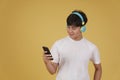 Portrait of happy joyful cheerful young asian man wearing headphones listening to music on smartphone and dancing isolated on Royalty Free Stock Photo