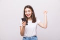 Portrait of a happy girl holding mobile phone and celebrating a win isolated over white background Royalty Free Stock Photo