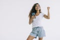 Portrait of a happy joyful girl holding mobile phone and celebrating a win over white background Royalty Free Stock Photo