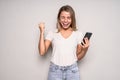 Portrait of a happy joyful girl holding mobile phone and celebrating a win over white background Royalty Free Stock Photo