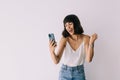 Portrait of a happy joyful girl holding mobile phone and celebrating a win over white background Royalty Free Stock Photo