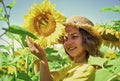 portrait of happy kid with beautiful sunflower. cheerful child in straw hat among yellow flowers. small girl in summer Royalty Free Stock Photo