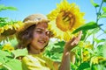 Portrait of happy kid with beautiful sunflower. cheerful child in straw hat among yellow flowers. small girl in summer Royalty Free Stock Photo