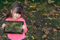 Portrait of happy kid holding tablet with both hands, showing it at camera while looking at screen with interested expression, sta