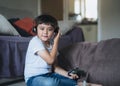 Portrait of happy kid holding video game or game console. Mixed race Child playing game online at home, Young boy siting floor Royalty Free Stock Photo