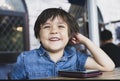 Portrait happy kid looking out with smiling face, Little boy watching cartoo or play games on mobile phone while waiting for food