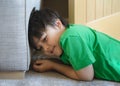 Portrait happy kid lying on carpet hiding behide sofa, Active child playing hide and seek, New normal lifte style, Relaxing boy Royalty Free Stock Photo