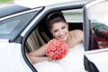 Portrait of happy laugh positive bride with bouquet. Sits in the car Royalty Free Stock Photo