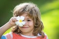 Portrait of a happy laughing child with eyes plumeria flower. Close up positive kids face. Covers eyes with flower Royalty Free Stock Photo