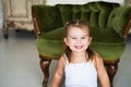 Portrait of a happy laughing child girl sitting on the floor near the antique chair