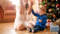 Portrait of happy laughing toddler boy throwing colorful confetti with mother on Christmas morning Royalty Free Stock Photo