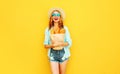 portrait happy laughing young woman holding paper bag with long white bread baguette, wearing straw hat, shorts on colorful yellow Royalty Free Stock Photo