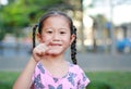 Portrait of happy little Asian child in garden with pointing at camera. Portrait smiling kid girl in summer park. Focus at Royalty Free Stock Photo