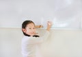 Portrait of happy little Asian child girl or Schoolgirl writing something on whiteboard with a marker and looking at camera in the Royalty Free Stock Photo