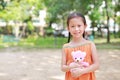 Portrait of happy little Asian child in green garden with hugging teddy bear and looking at camera. Close up smiling kid girl in Royalty Free Stock Photo