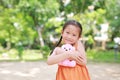Portrait of happy little Asian child in green garden with hugging teddy bear and looking at camera. Close up smiling kid girl in Royalty Free Stock Photo