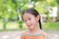 Portrait of happy little Asian child in green garden with looking at camera. Close up smiling kid girl in summer park Royalty Free Stock Photo