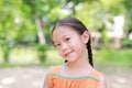 Portrait of happy little Asian child in green garden with looking at camera. Close up smiling kid girl in summer park Royalty Free Stock Photo