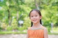 Portrait of happy little Asian child in green garden with looking at camera. Close up smiling kid girl in summer park Royalty Free Stock Photo