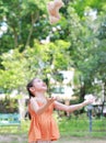 Portrait of happy little Asian child in green garden with throwing up teddy bear doll floating on air. Smiling kid girl playing in Royalty Free Stock Photo