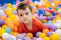 Portrait of a happy little boy jumping merrily into a dry pool with colorful balloons. A toddler boy is playing and Royalty Free Stock Photo