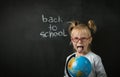 Elementary school student holding the globe on the black school board background Royalty Free Stock Photo