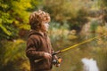 Portrait of happy little child son fishing on river with spinning reel. Happy kids autumn weekend concept.